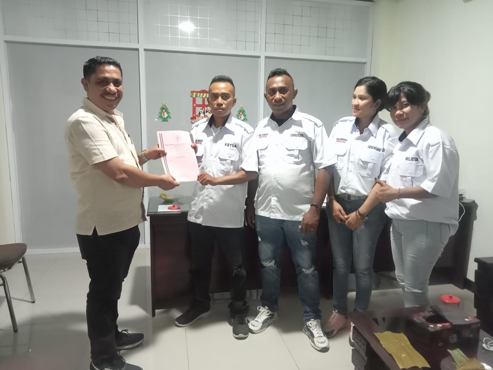 Notaris, Yerak Almodat Bobilex Pakh, S.H., M.Kn, menyerahkan akta notaris Relawan Milenial Proyos kepada Ketua Relawan Milenial Proyos, Lengky Sallu, didampingi Sekretaris Relawan Milenial Proyos, John Manek (tengah) dan pengurus Relawan Milenial Proyos. Foto : istimewa. 